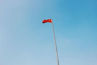 Low angle view of flag against clear blue sky