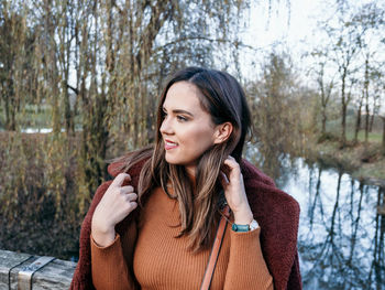 Portrait of happy young woman in winter clothes in park.