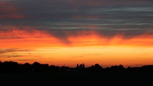 Silhouette landscape against dramatic sky during sunset