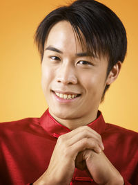 Portrait of man gesturing while standing against orange background