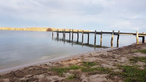 Wooden posts on beach against sky
