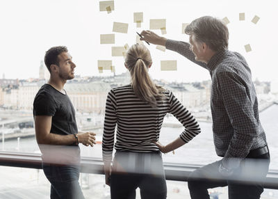 Businessman explaining adhesive notes to colleagues in office