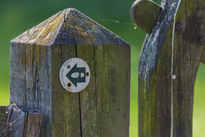 Close-up of wooden post with information sign