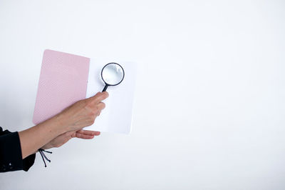 Cropped hand holding stethoscope against white background