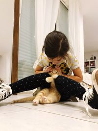 Girl with cat sitting on floor at home