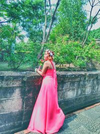 Woman standing on pink flower against trees