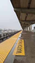 Road sign on bridge against sky