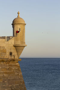 Lighthouse by sea against sky