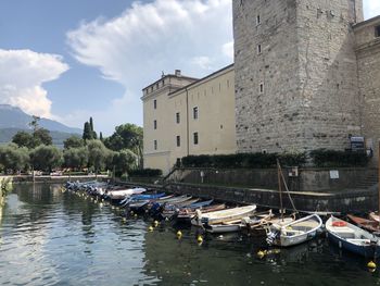 Sailboats moored on river by buildings in city against sky