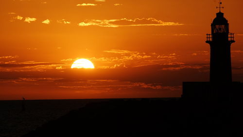 Silhouette lighthouse against sky during sunset