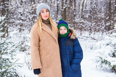 Portrait of mother with son standing against trees during winter