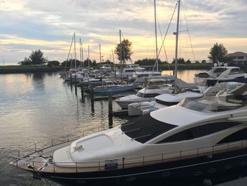 Boats moored at harbor against sky during sunset