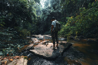 Man standing on rock by river in forest