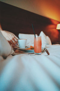 Cropped hands of woman holding coffee cup on bed