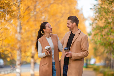 Young woman standing by tree during autumn