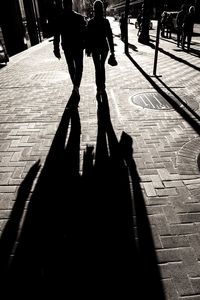Low section of silhouette people walking on road