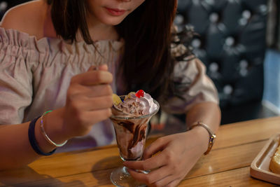 Midsection of woman holding drink on table