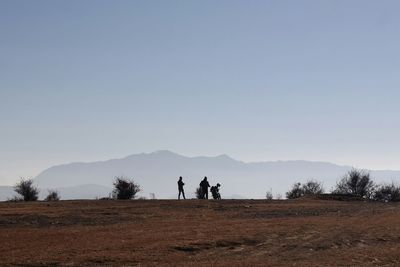 Men standing on field against clear sky