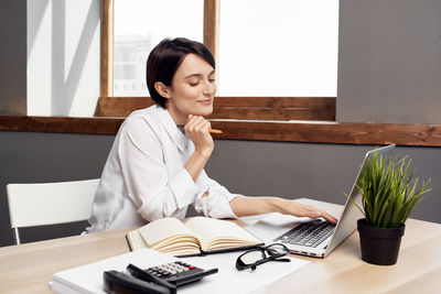 Young woman using phone while sitting on table