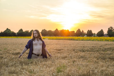 Portrait of young woman on field against sky during sunset