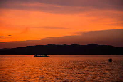 Boat sailing in sea at sunset