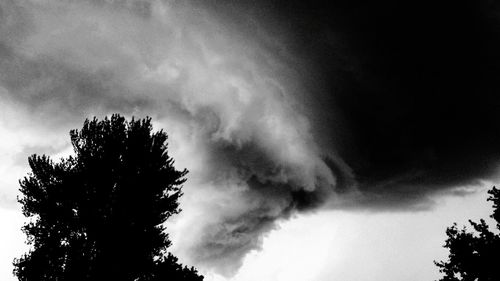 Low angle view of silhouette tree against storm clouds