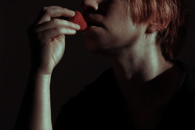 Midsection of man holding ice cream against black background