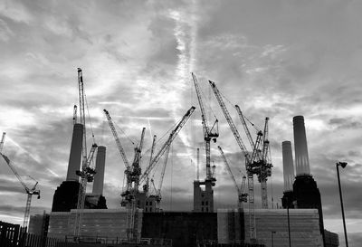 Low angle view of cranes at construction site against sky