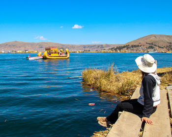 Rear view of man standing in sea against clear blue sky