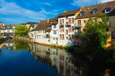 Houses by river in town against sky