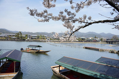 Boats moored on lake by city against sky