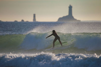 Man surfing in sea against sky