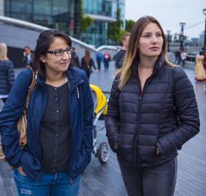 Female friends looking away while standing in city