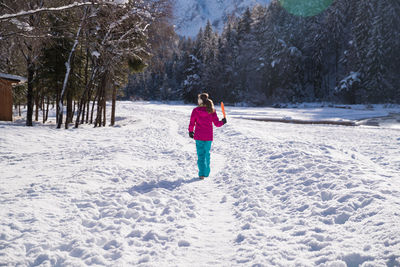 Rear view of woman standing on snow covered land