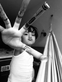 Portrait of boy with arms raised standing at home