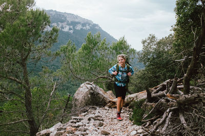 Portrait of woman standing on mountain against trees