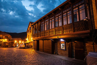 Illuminated street amidst buildings at night