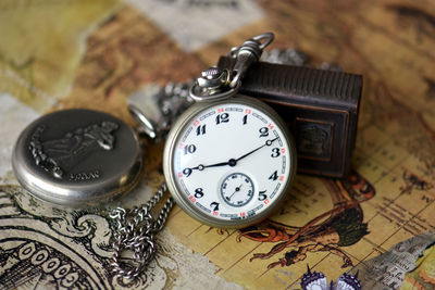 Close-up of pocket watches on map