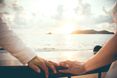 Midsection of couple kissing against sea