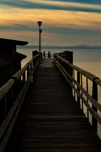 Pier amidst sea against sky during sunset