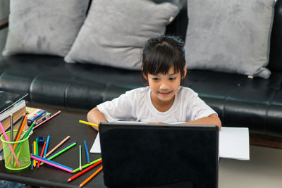 Rear view of boy using mobile phone at home