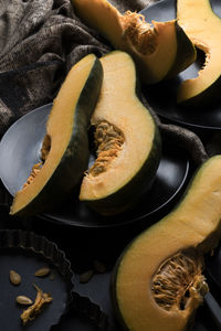 Pieces of sliced pumpkin on the dark table with dark dishes