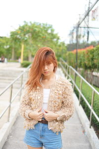 Young woman looking away while standing on mobile phone