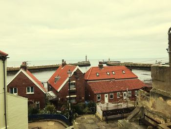 Houses by sea against sky