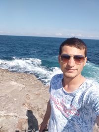 Portrait of man wearing sunglasses at beach against sky