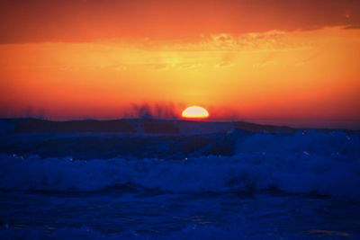 Scenic view of landscape against orange sky during sunset