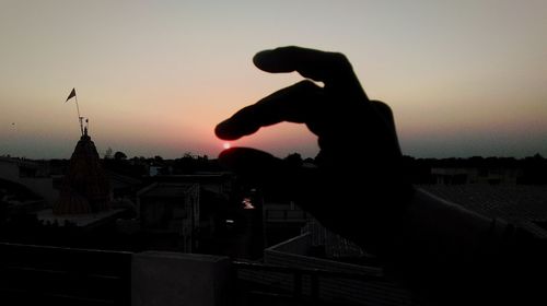 Silhouette of woman photographing sunset