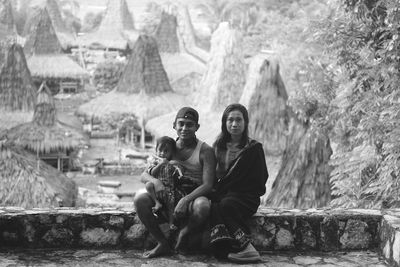 Portrait of family sitting on curb in village