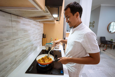 Side view of young man having food at home