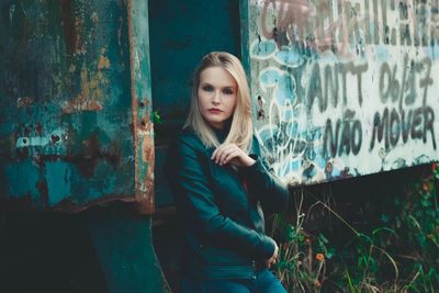 Portrait of young woman standing against wall